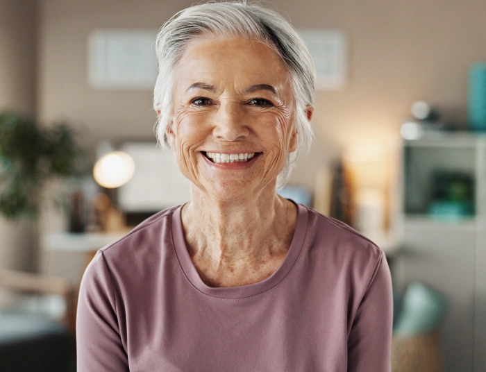Smiling older woman in purple shirt, modern dental office interior background