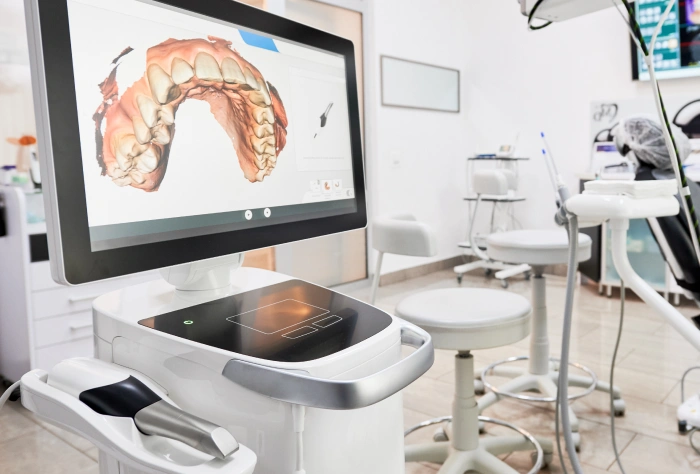 Dental office showing digital scanner, monitor displaying teeth model, and orthodontic equipment.